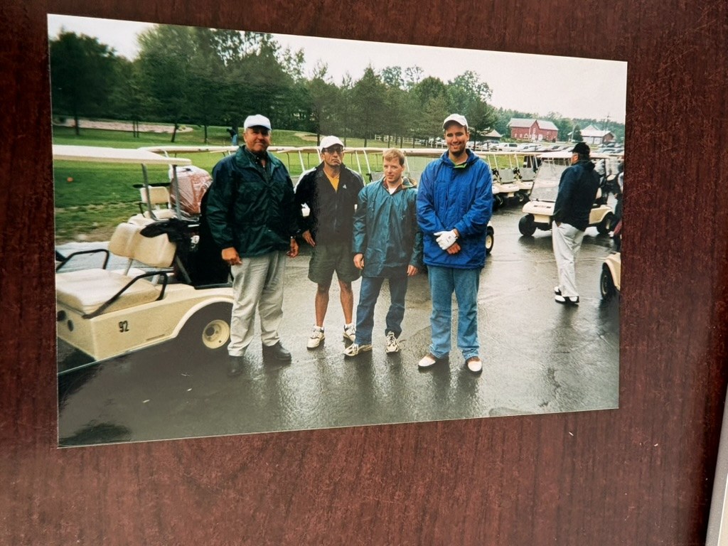 Younus Samadzada with friends beside golf carts on a rainy day